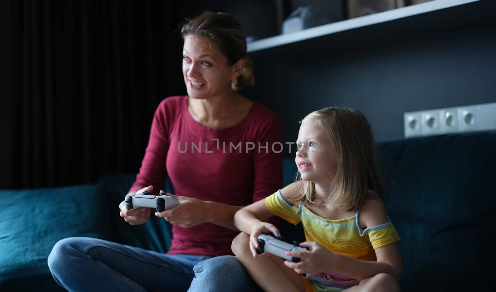 Mom and daughter hold game joysticks and play online games. Family games in game console concept