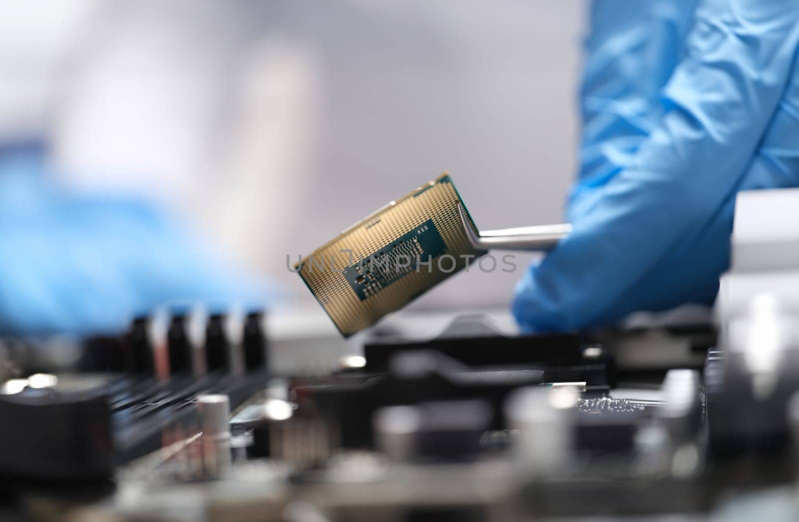 Engineer is holding microprocessor tweezers from motherboard. Microchip testing concept