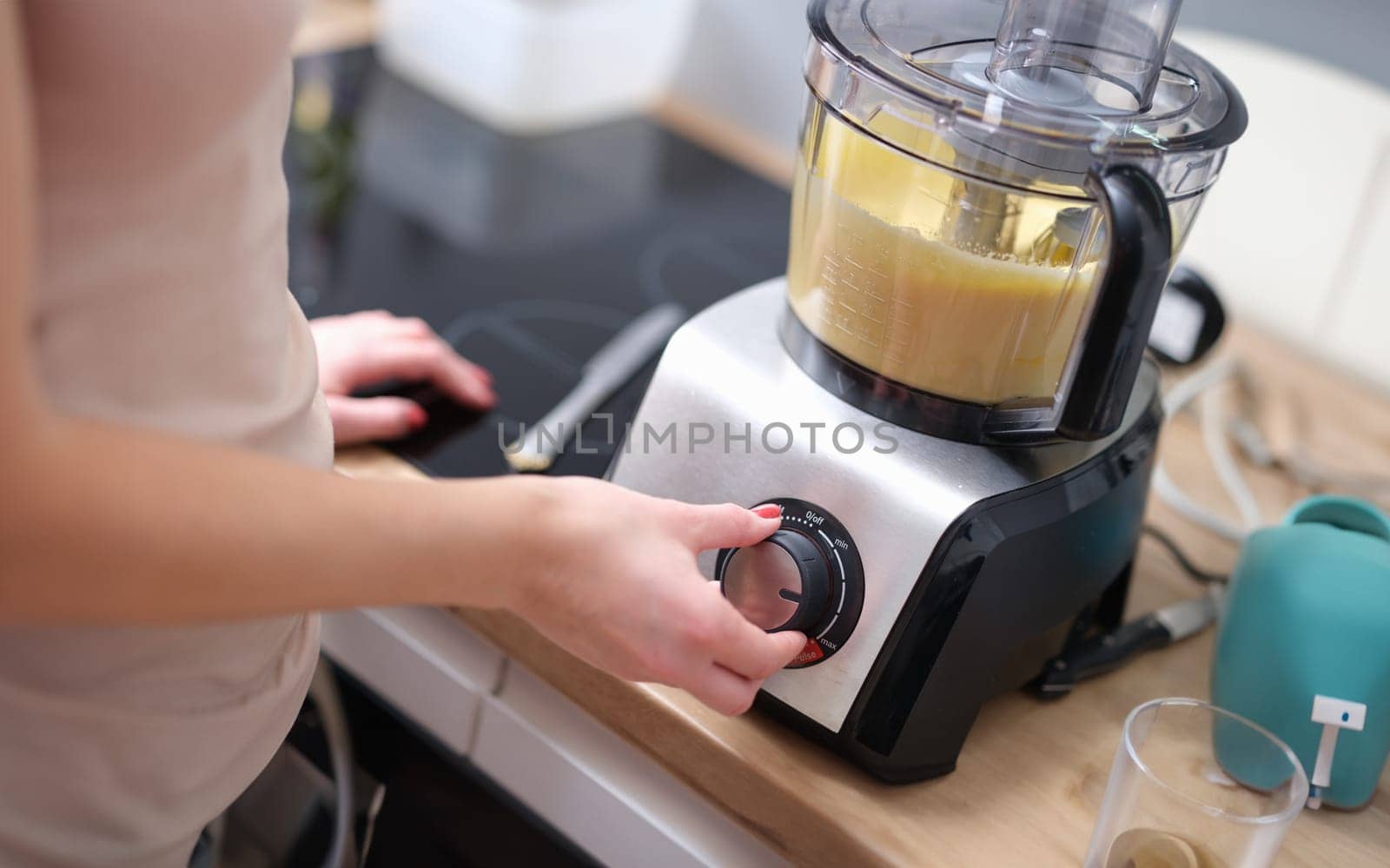 Woman adjusting speed of food processor. Pastry chef in kitchen turns on mixer or food processor concept