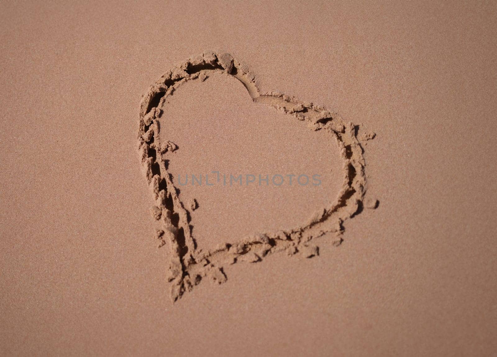 Heart is painted on sand of sea beach closeup. Honeymoon romantic trip concept