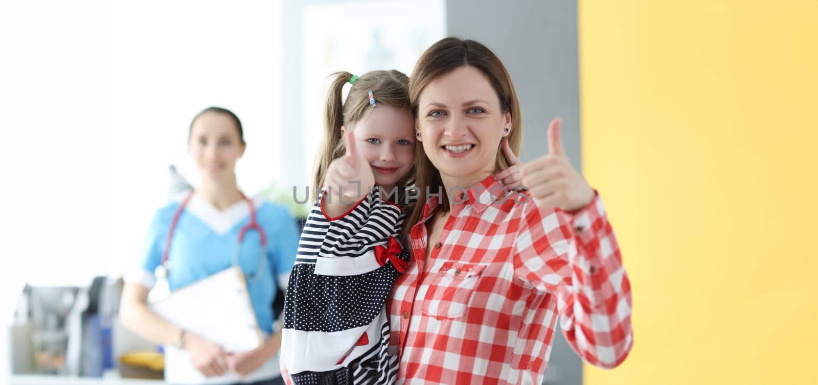 Little girl and mom showing thumb up at doctor appointment by kuprevich