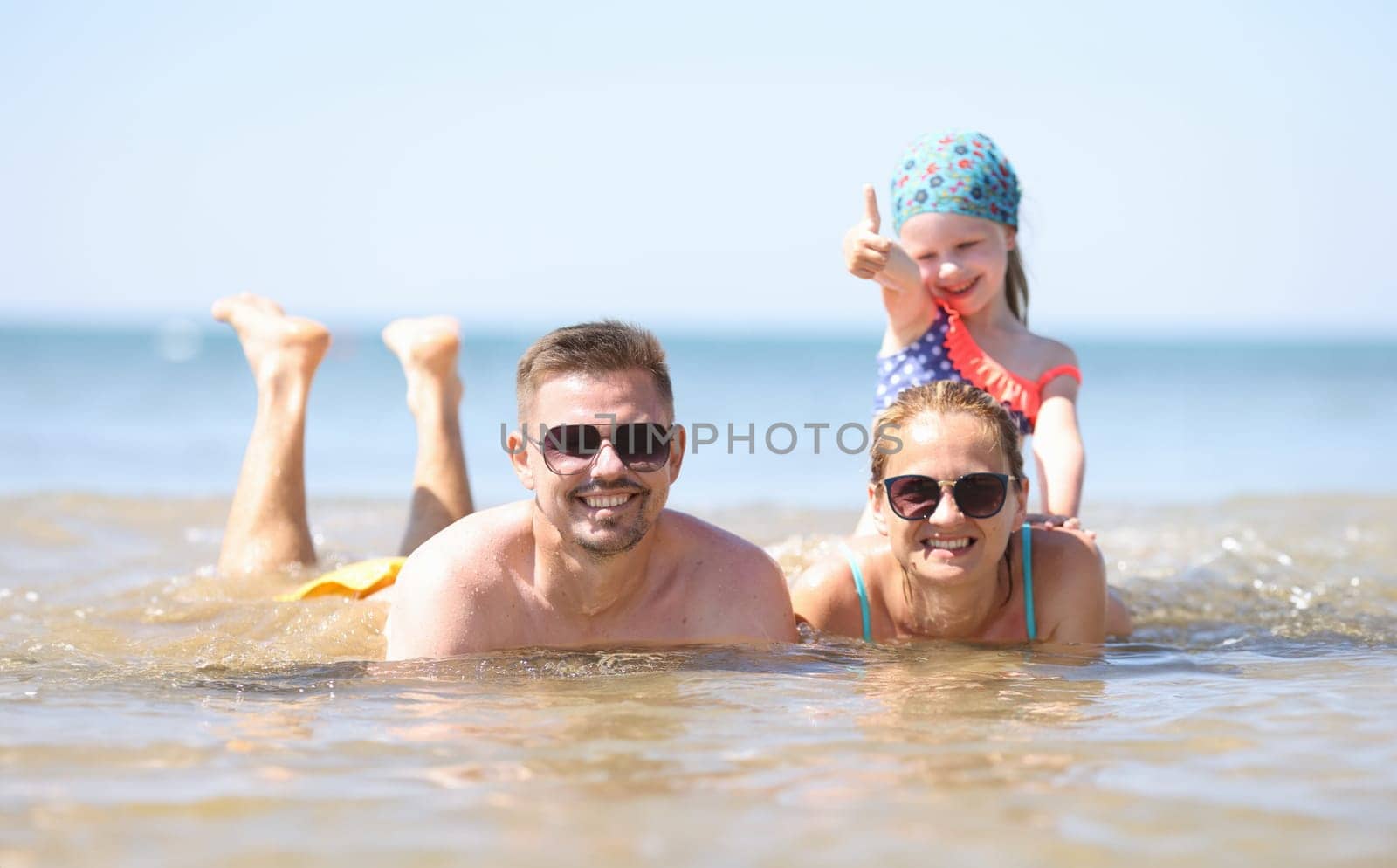 Family with little girl lying in sea. Family vacation concept