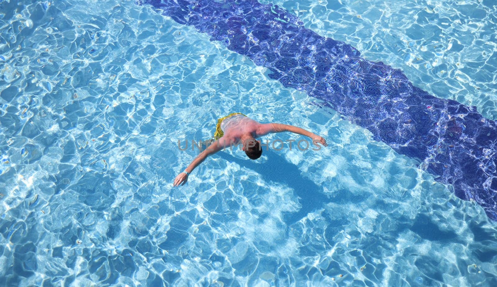 Young man swimming in pool top view. Recreation on water concept