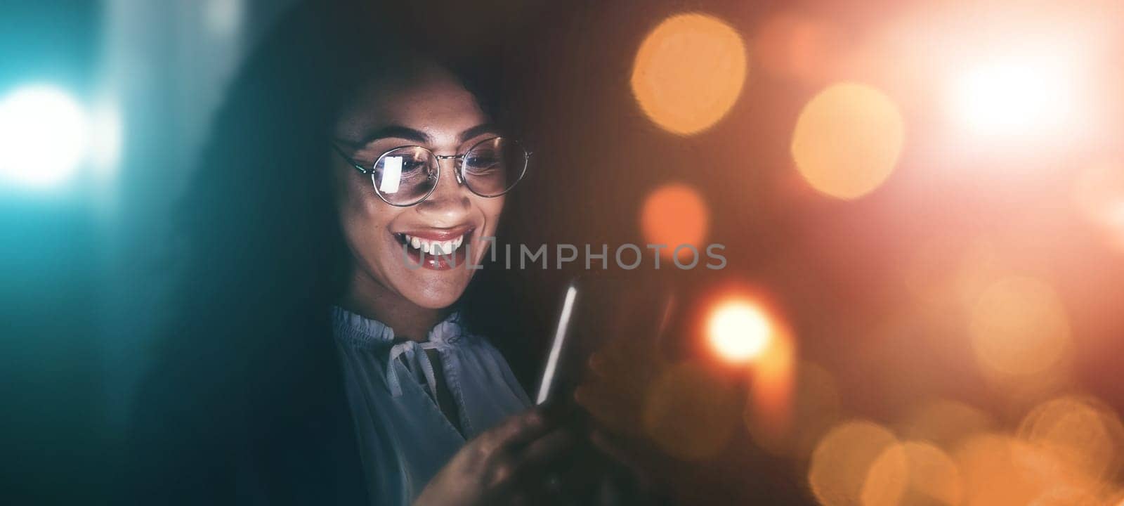 Businesswoman, phone and smile in communication at night for texting, chatting or networking on dark background. Happy female employee holding smartphone working late for online planning strategy.