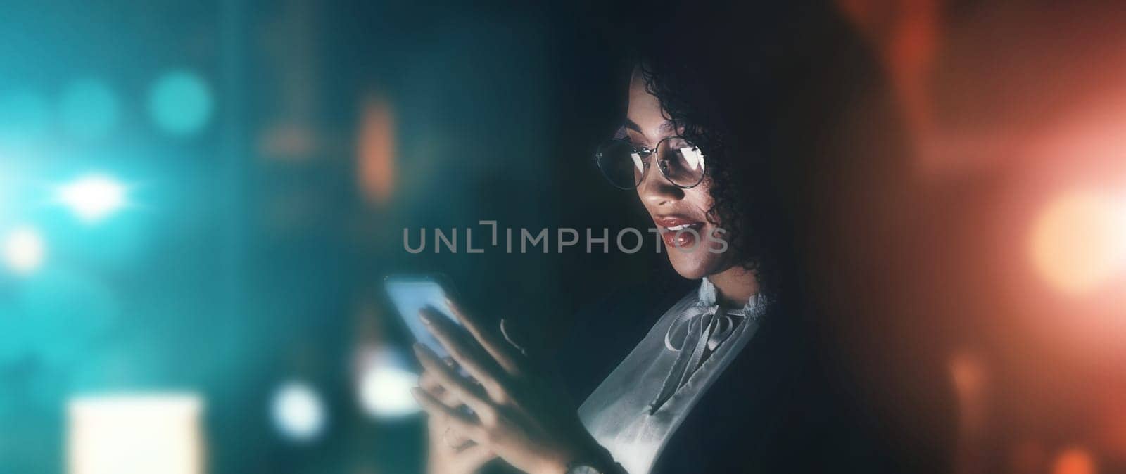 Businesswoman, phone and communication at night for networking, chatting or texting on dark background. Female employee holding smartphone working late at the office for online planning strategy.