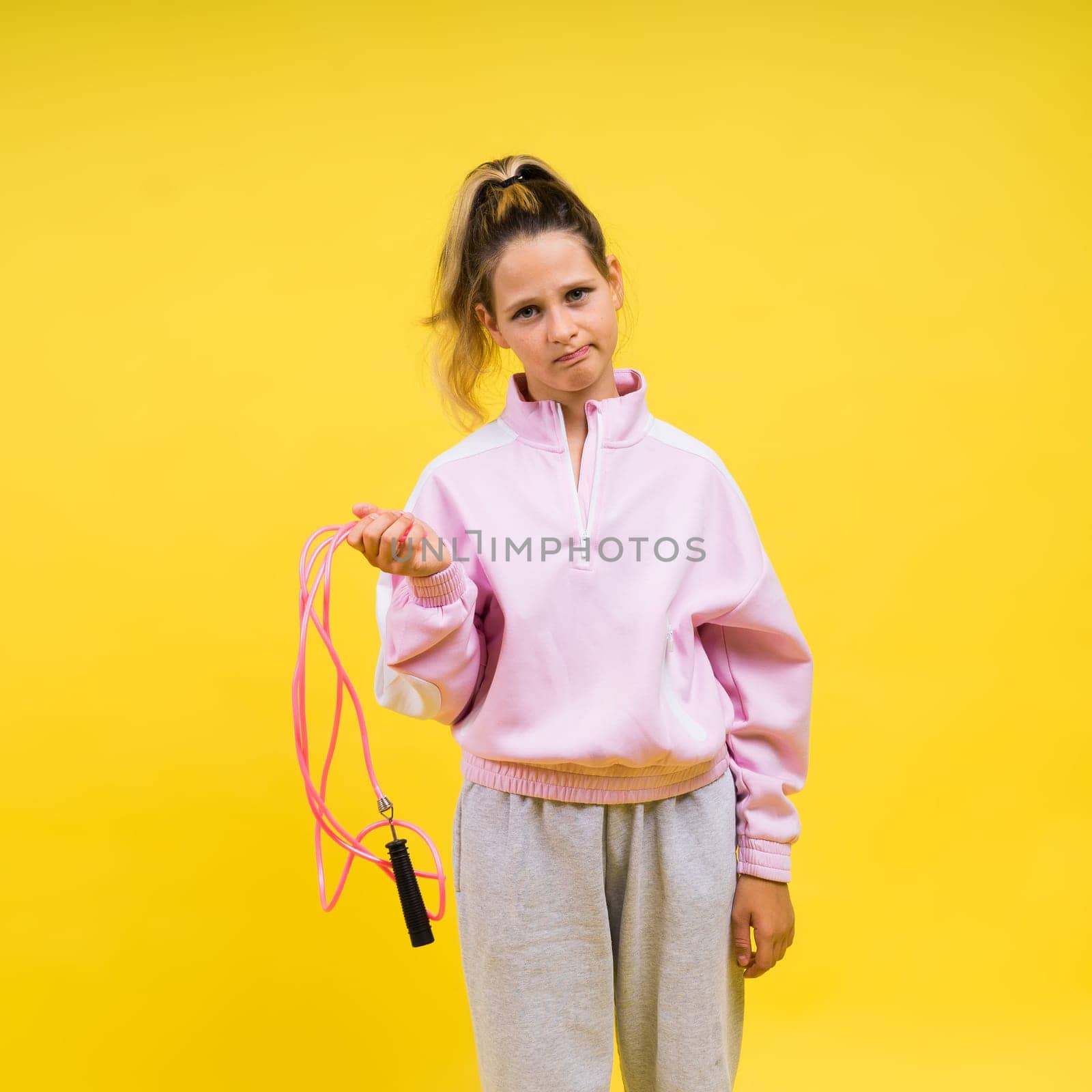 Beautiful sportsgirl with skipping rope isolated on a yellow studio
