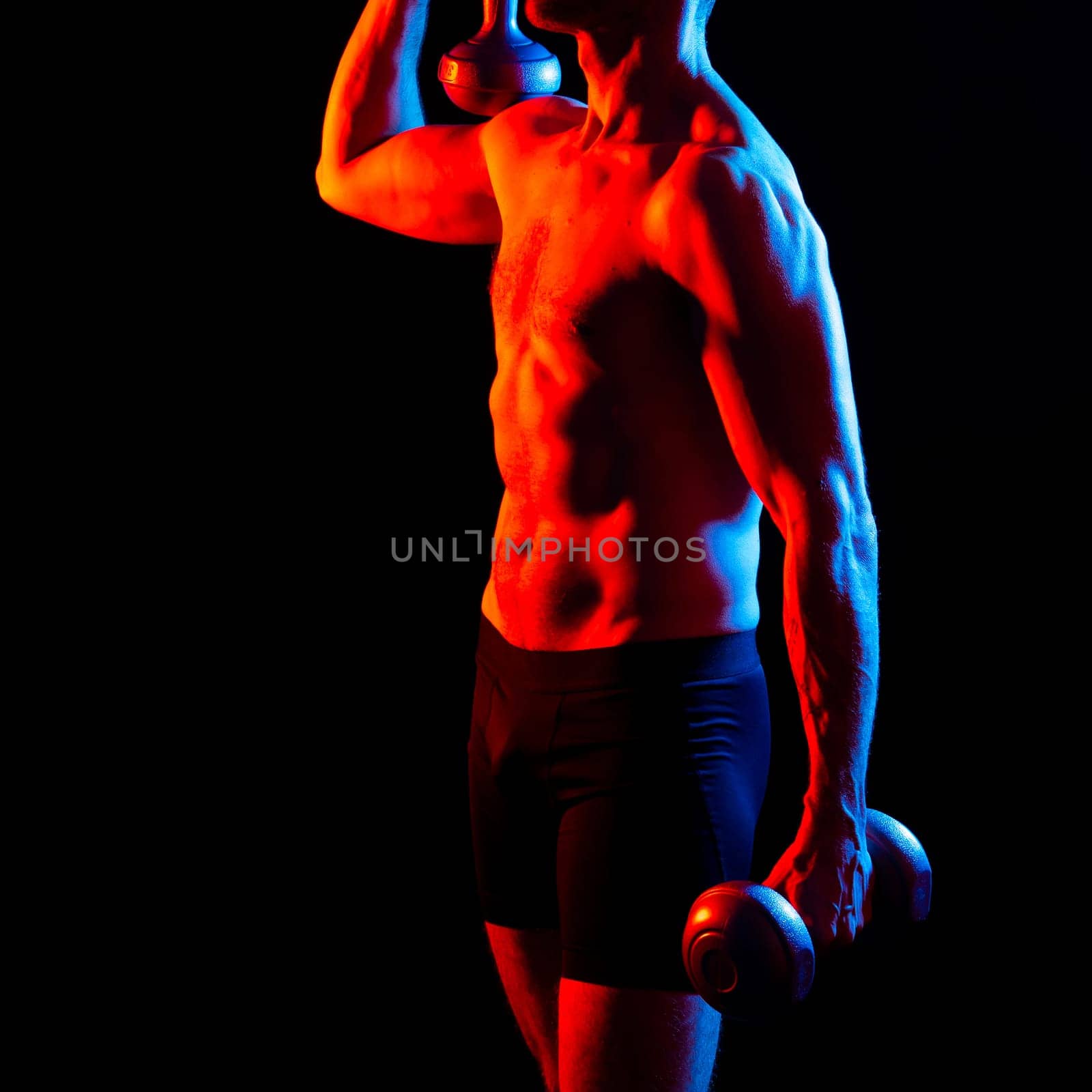 Handsome young fitness sporty strong guy bare-chested muscular sportsman on a studio background