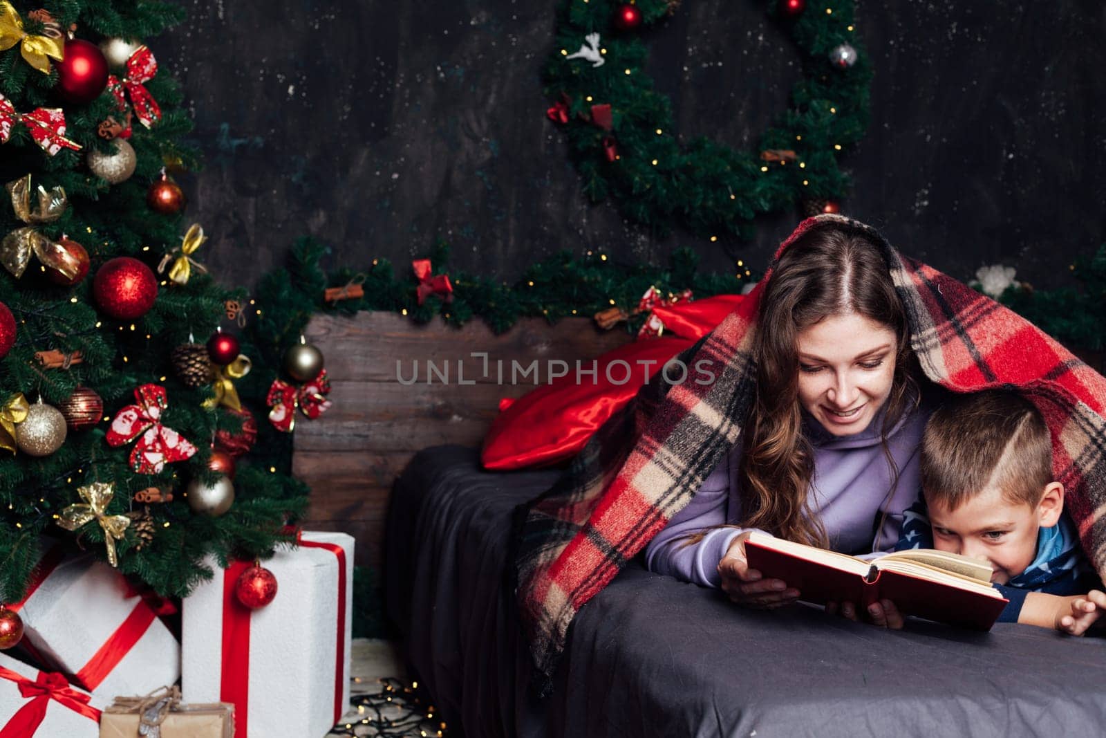Mom with son on bed at christmas tree with gifts