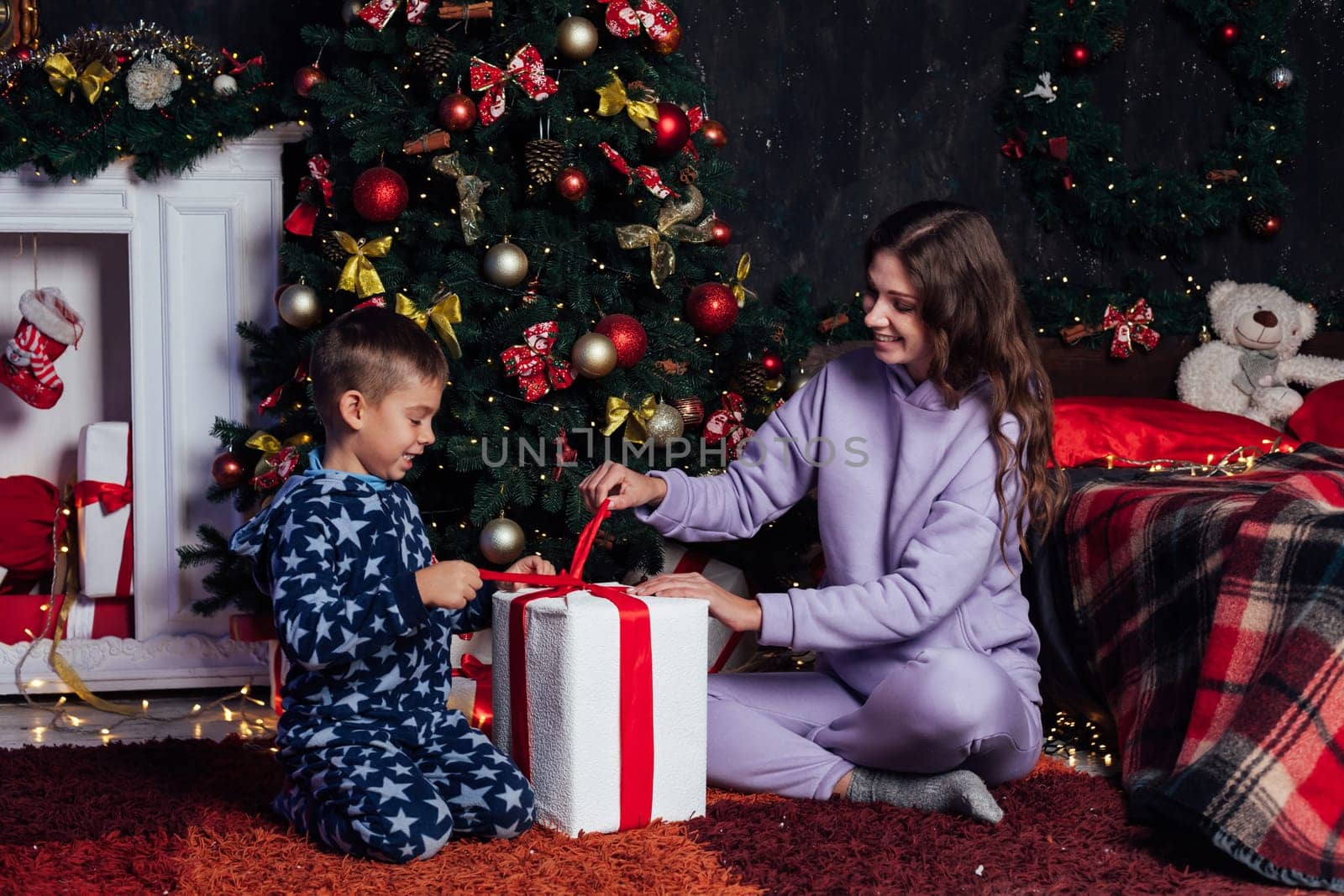 Mom with son at christmas tree with gifts new garland winter by Simakov