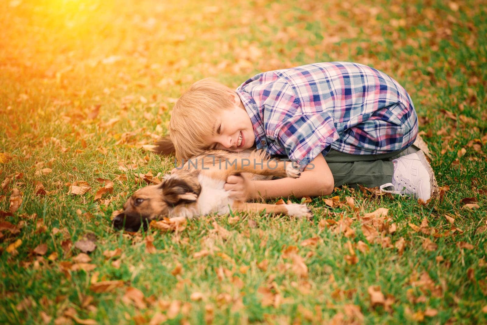 Cute boy playing and walking with his dog in the meadow.