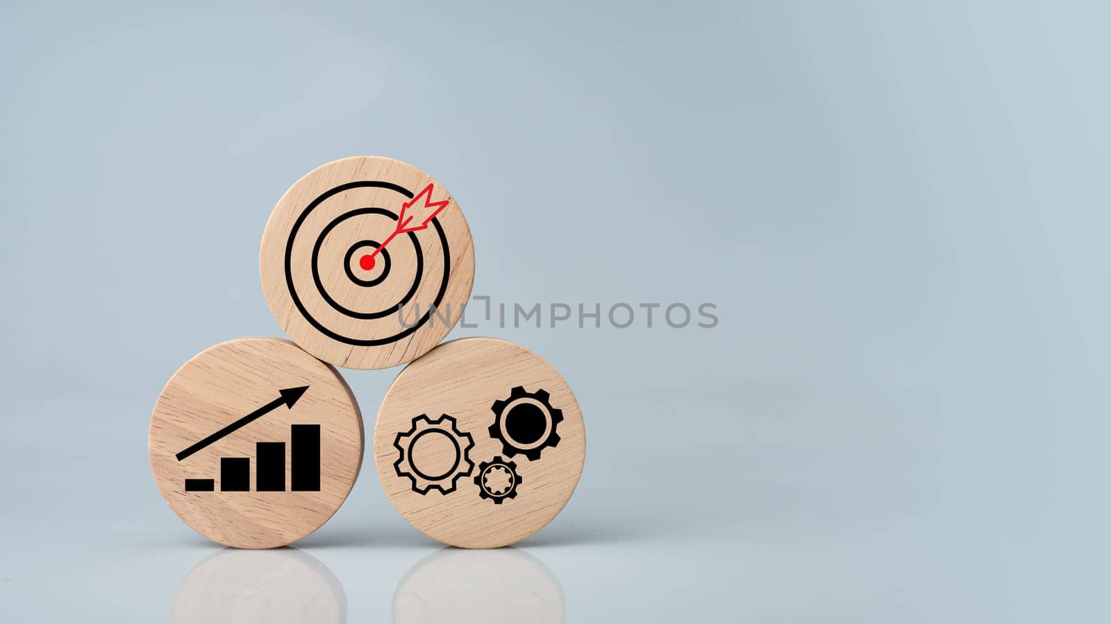 Circular wood with printed target icons and business symbols on white background, business goals and objectives concept, business competition. by Unimages2527