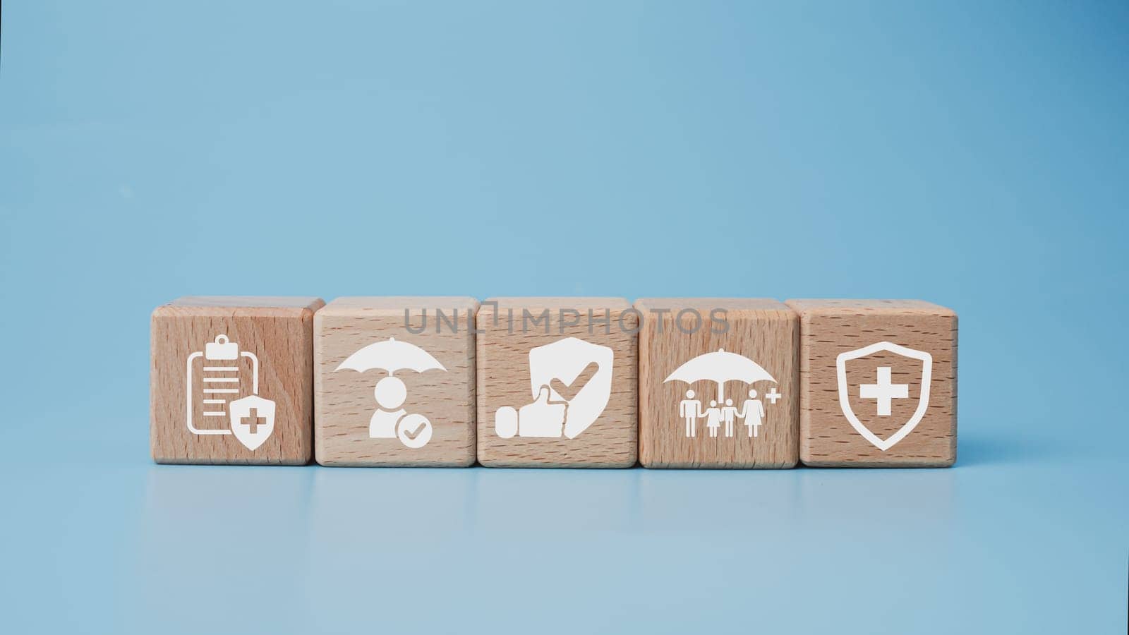 Concept of health insurance and medical. Wooden block with icons about health insurance and access to health care, health care planning on a blue background. by Unimages2527