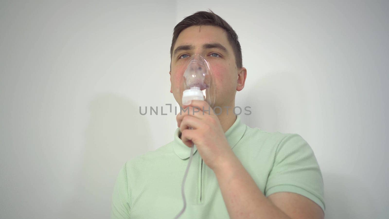 A young man breathes through an inhaler closeup. A man with an oxygen mask is being treated for a respiratory infection. 4k