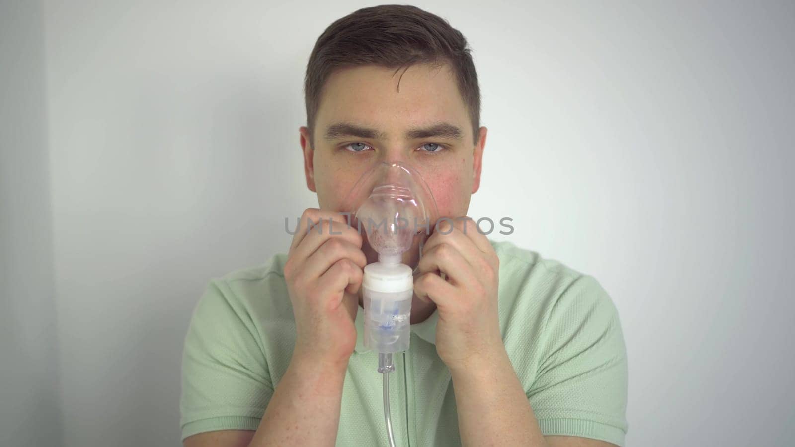 A young man breathes through an inhaler closeup. A man with an oxygen mask is being treated for a respiratory infection. 4k