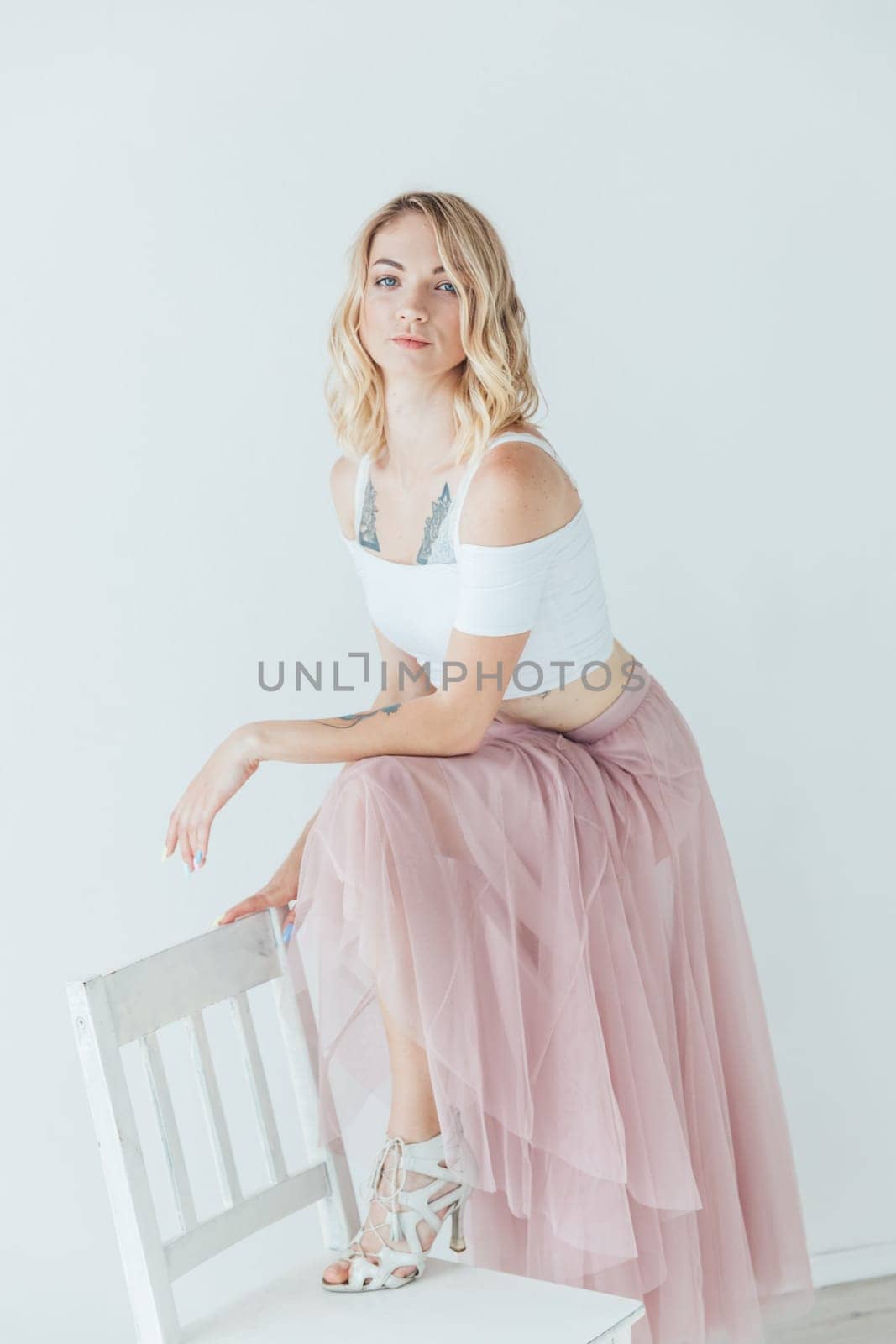 Tender beautiful woman posing on a chair in a bright room by Simakov