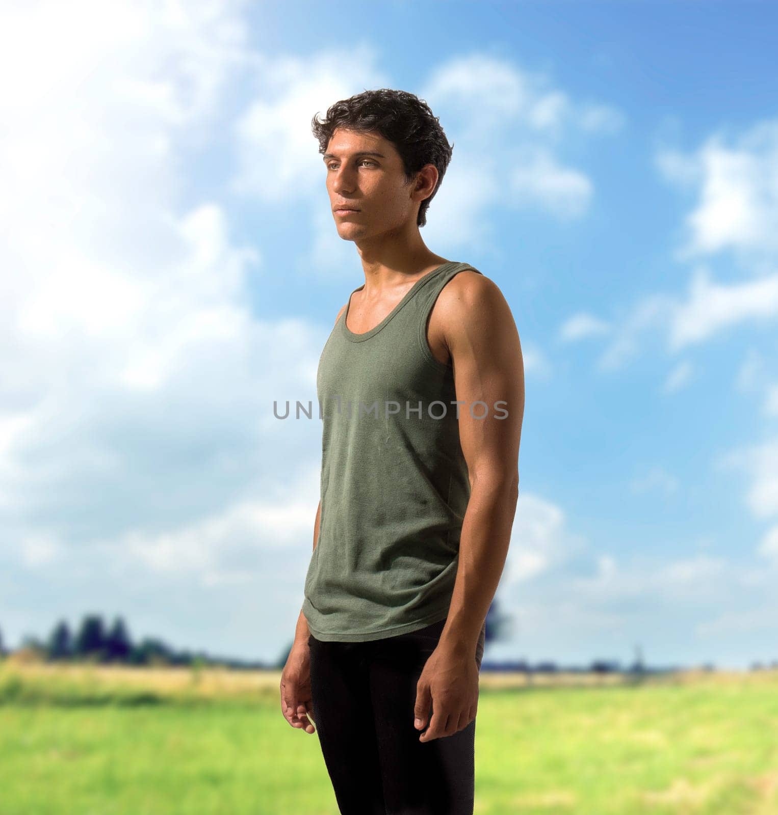 A Handsome and Athletic Young Man Standing in a Field by artofphoto
