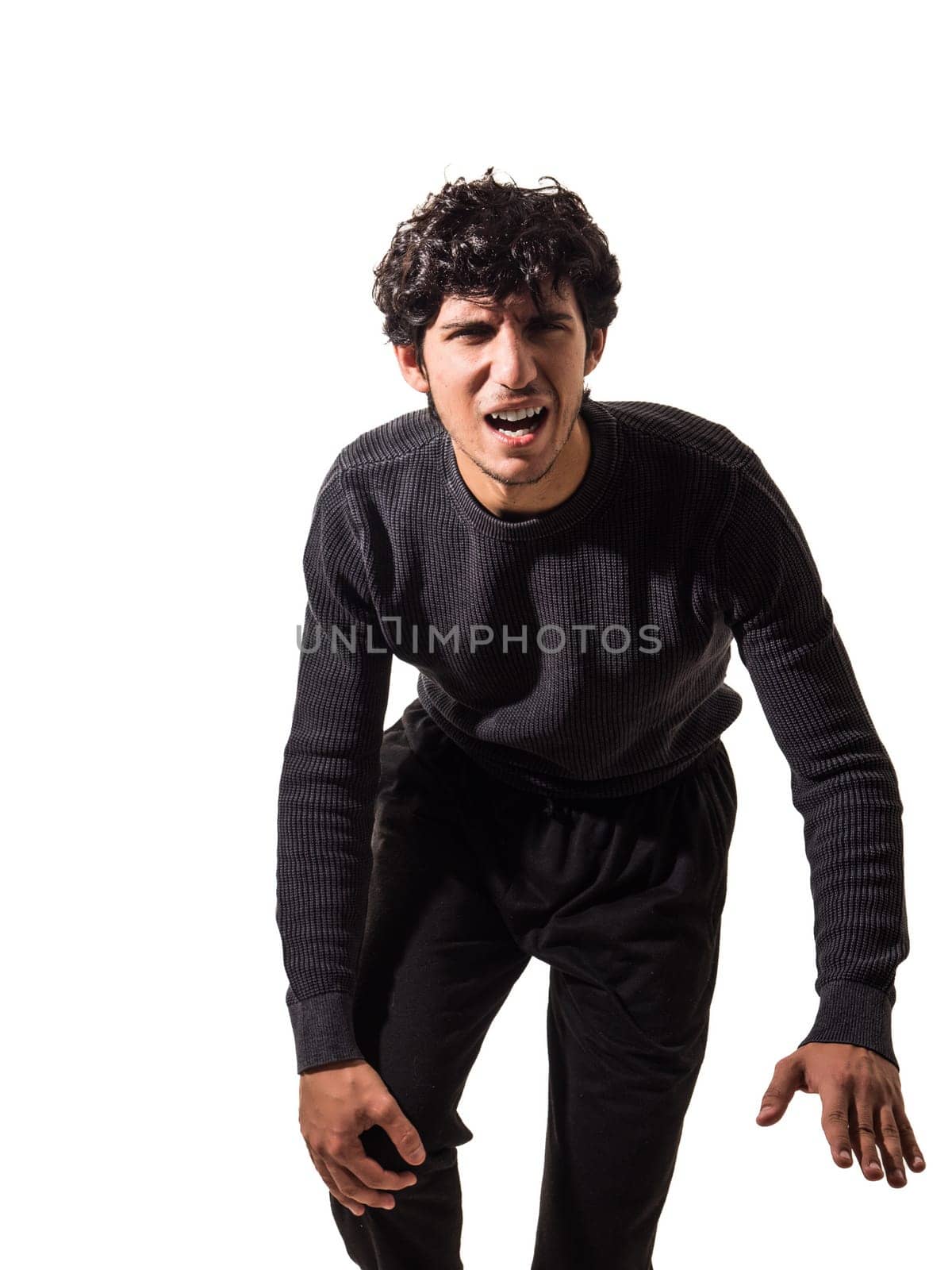 A man in a black sweater and black pants, experiencing pain to his knee, with aching leg