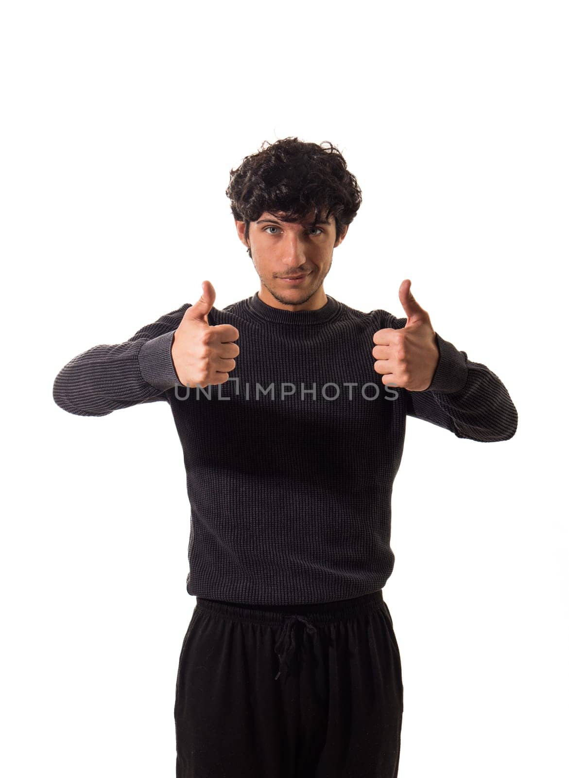 A man in a black sweater giving a thumbs up, in studio shot on neutral background