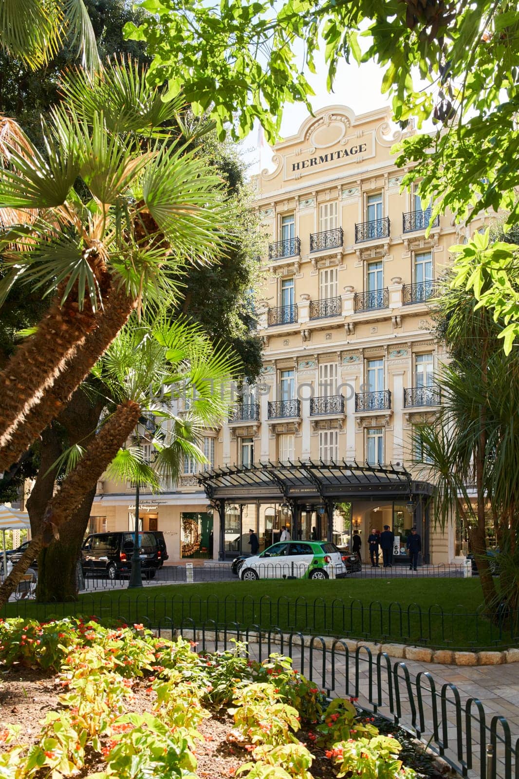 Monaco, Monte-Carlo, 09 November 2022, The Hotel Hermitage through flowers at sunny day, luxury life, building exterior of famous hotel, palm trees, sunshine, balcony. High quality photo