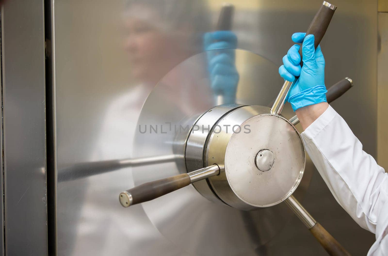 A worker's hand turns a valve in a pharmaceutical or medical device manufacturing plant.