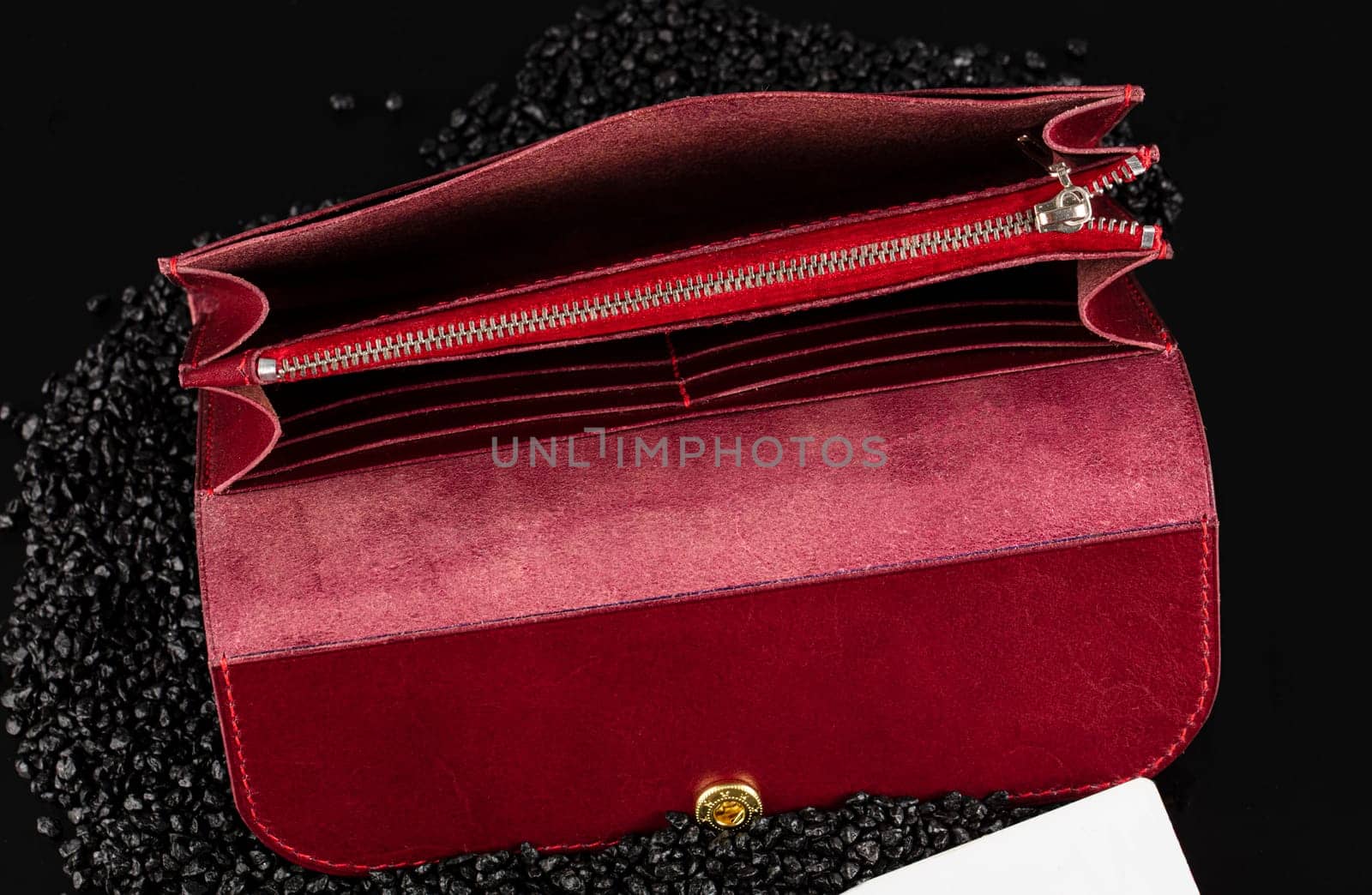 Open red leather wallet and purse on a black background.