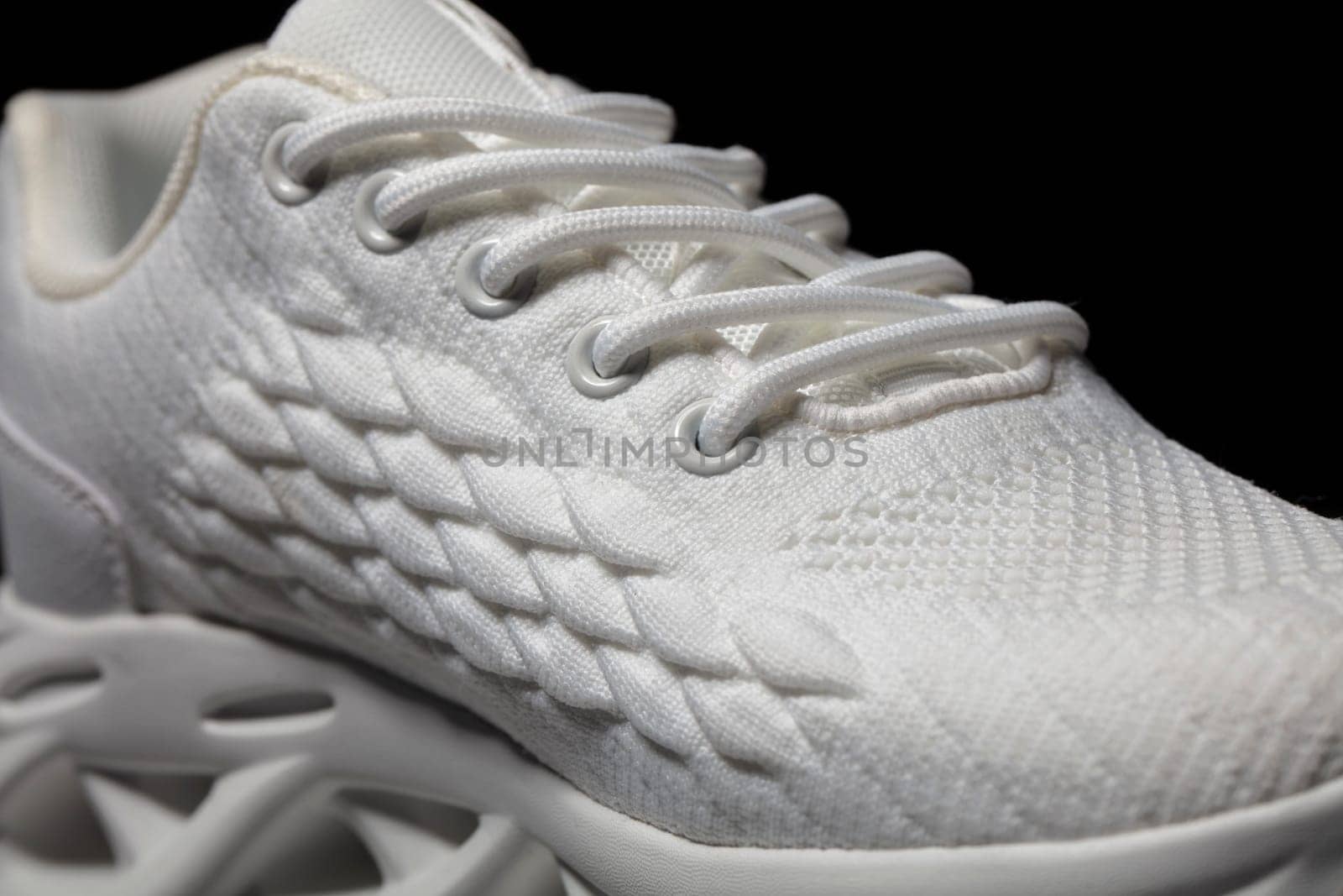 Part of a white fabric sneaker on a dark background.