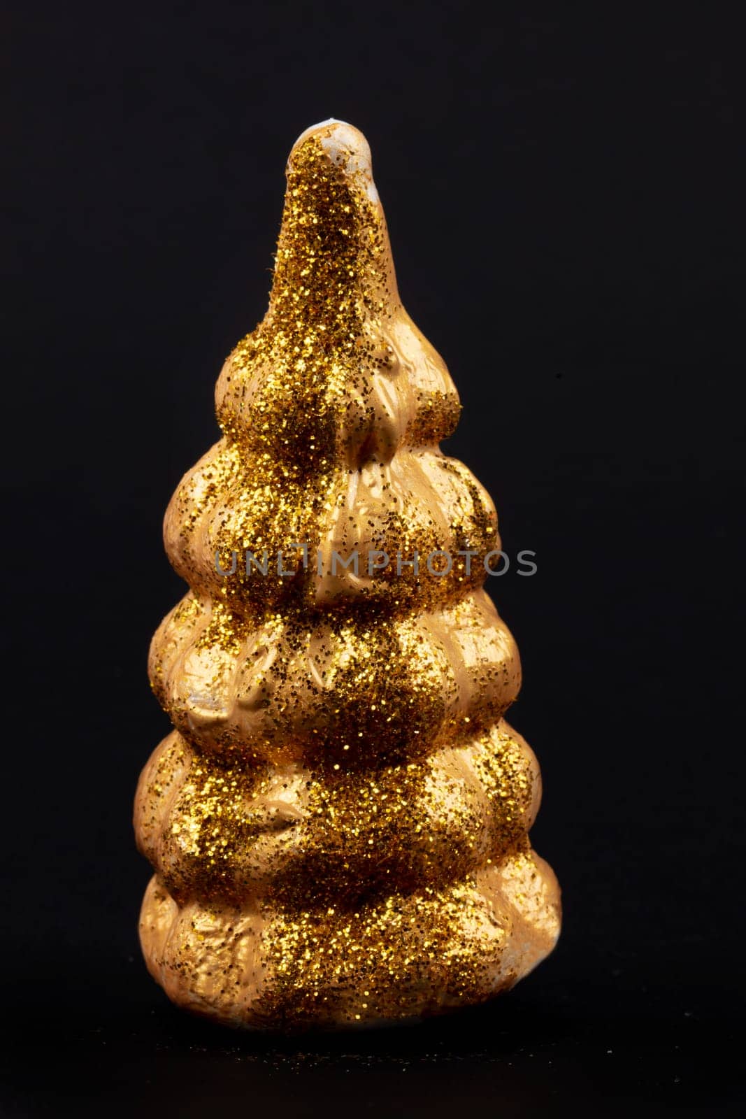 Christmas composition.Gold toy Christmas tree on a black background. Happy Holidays. Minimal new year concept.