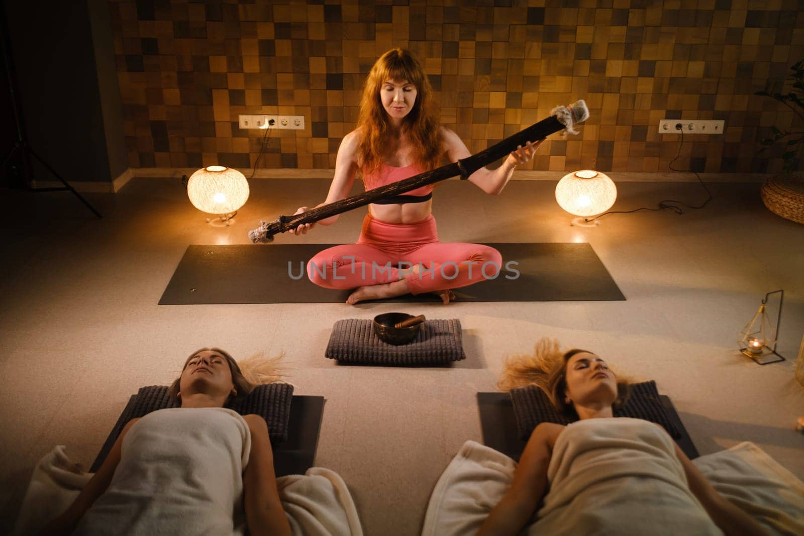 girls, lying on the floor, relax under the sound instrument of the rain staff in the fitness room by Lobachad