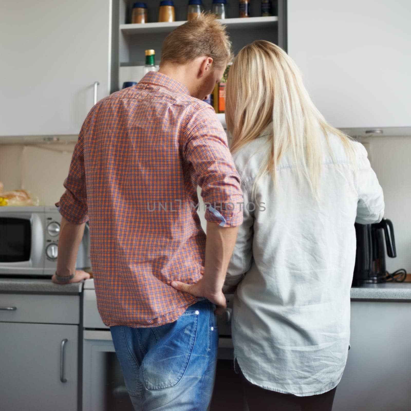 Cooking, back and couple in a kitchen for breakfast, meal or bonding at home together. Love, food and rear view of people in a house for meal prep, brunch or preparing dinner on weekend or day off by YuriArcurs