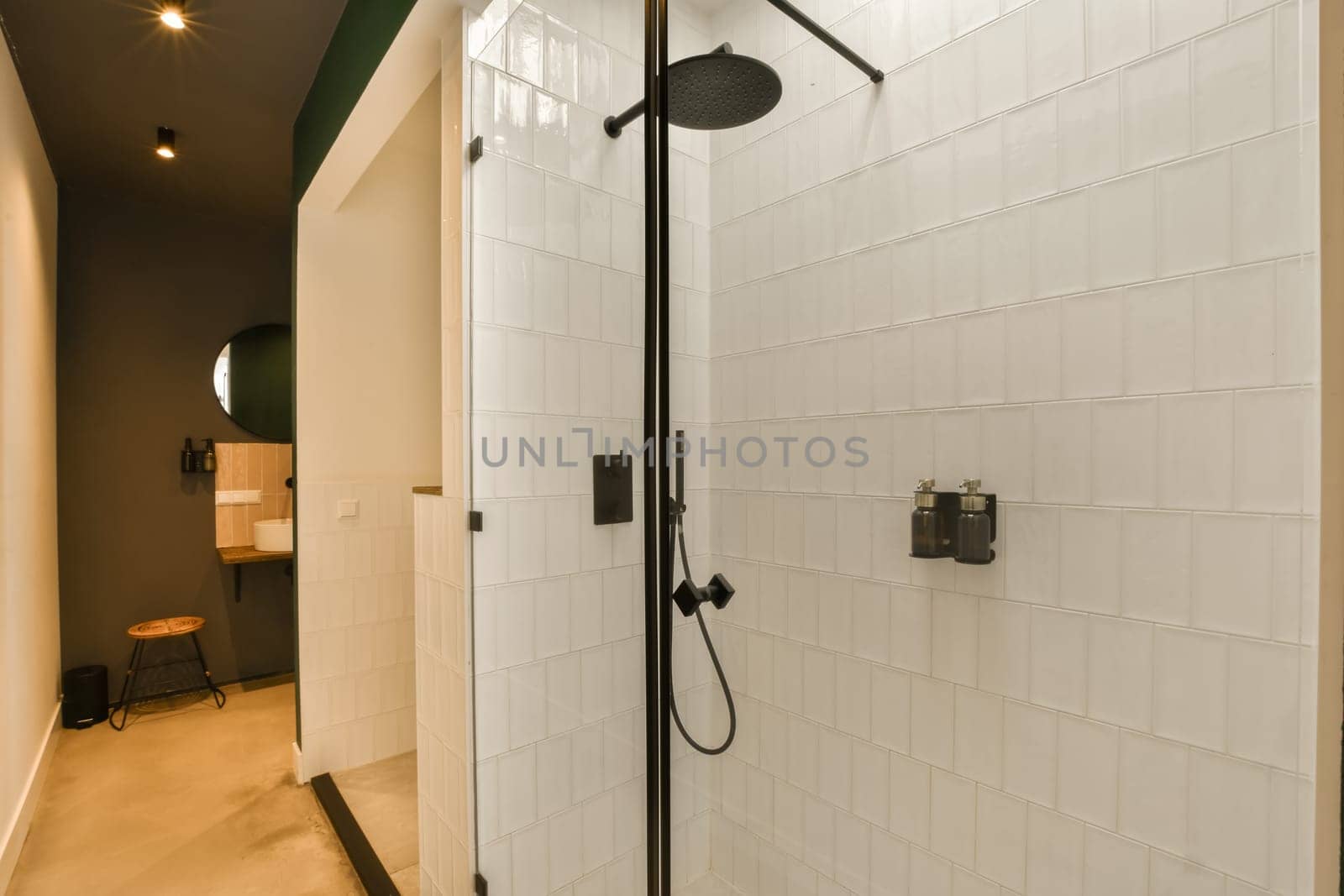 a bathroom with white tiles on the walls and black trim around the shower head, which is attached to the wall