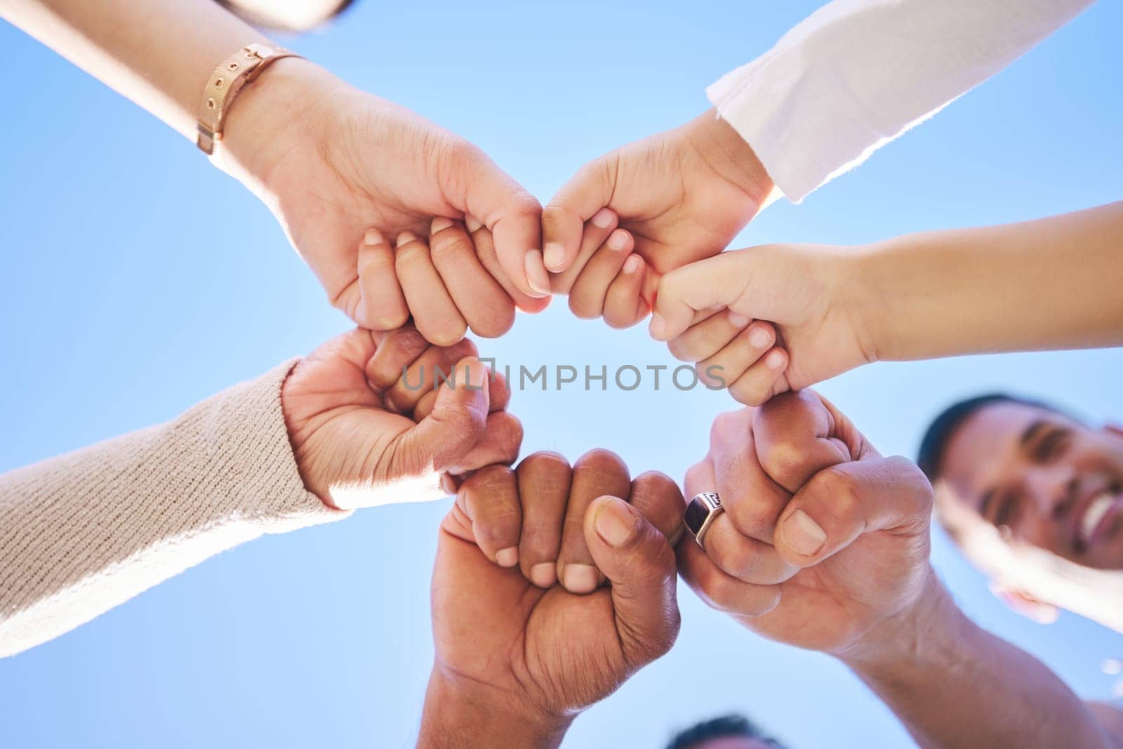 Big family, fist bump and teamwork synergy in circle for support, trust or unity in collaboration outdoors. Low angle of people or friends touching hands for team building, community or goals outside by YuriArcurs