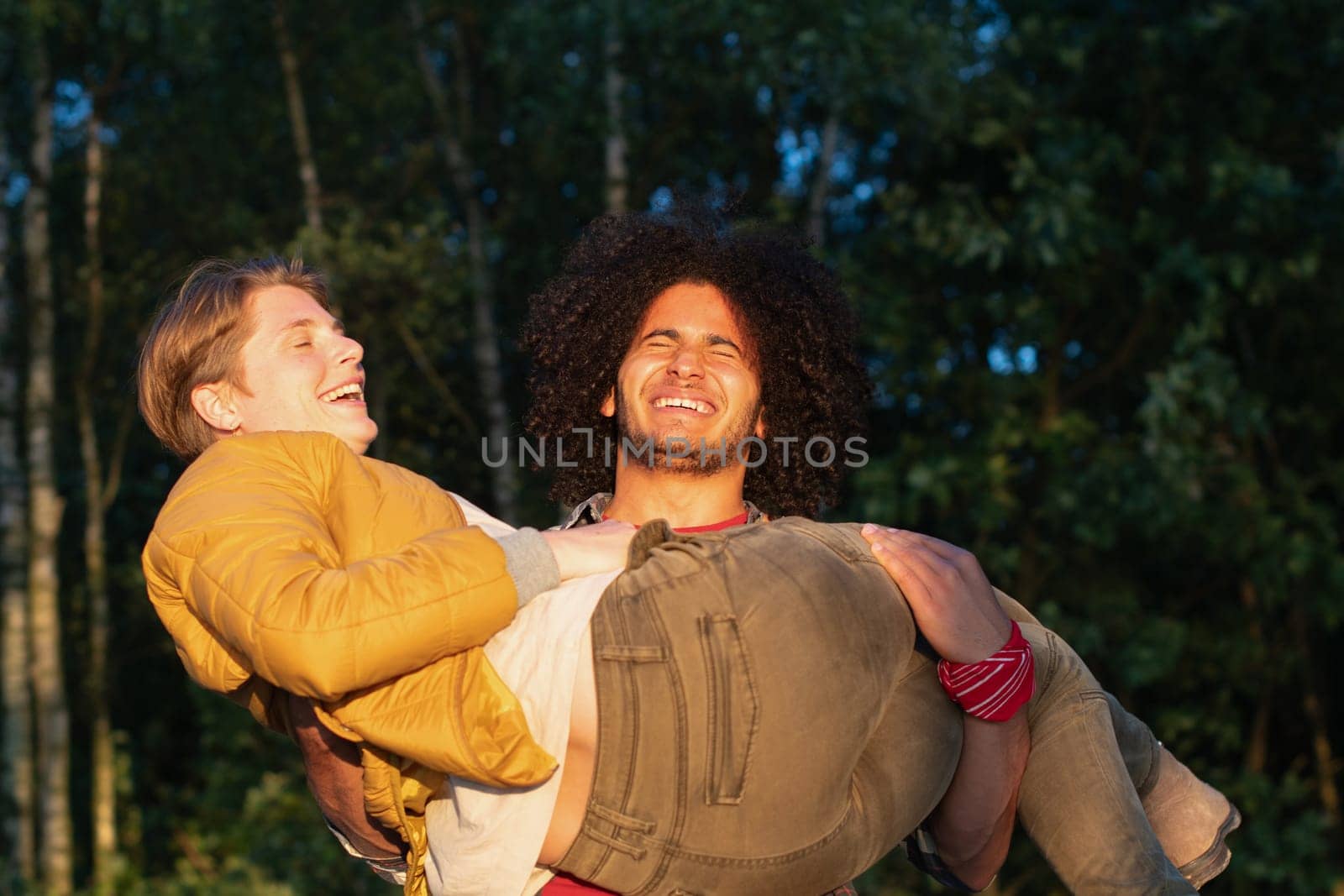 Close up of young adult couple piggybacking outdoors, side view. High quality photo