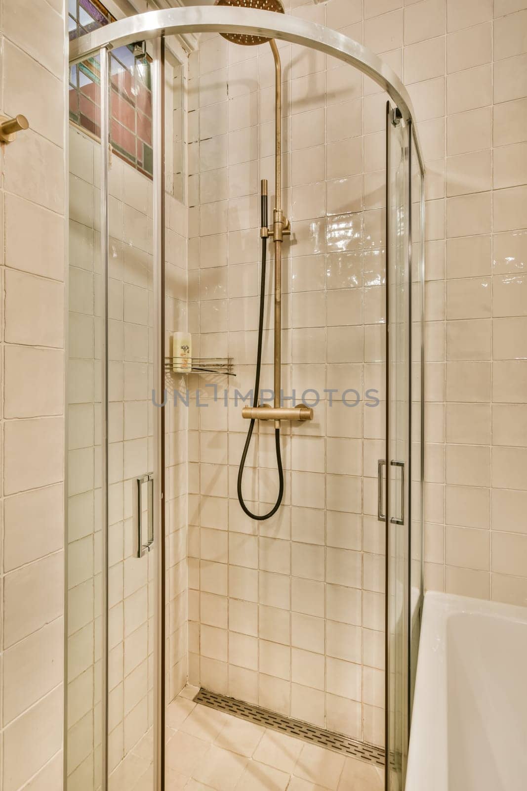 a bathroom with a glass shower door and tiled walls in the corner to the left is a white bathtub on the right side