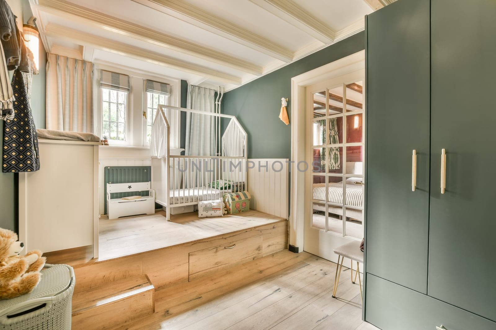 a room with blue walls and wood flooring, including an open door that leads to a bed in the corner