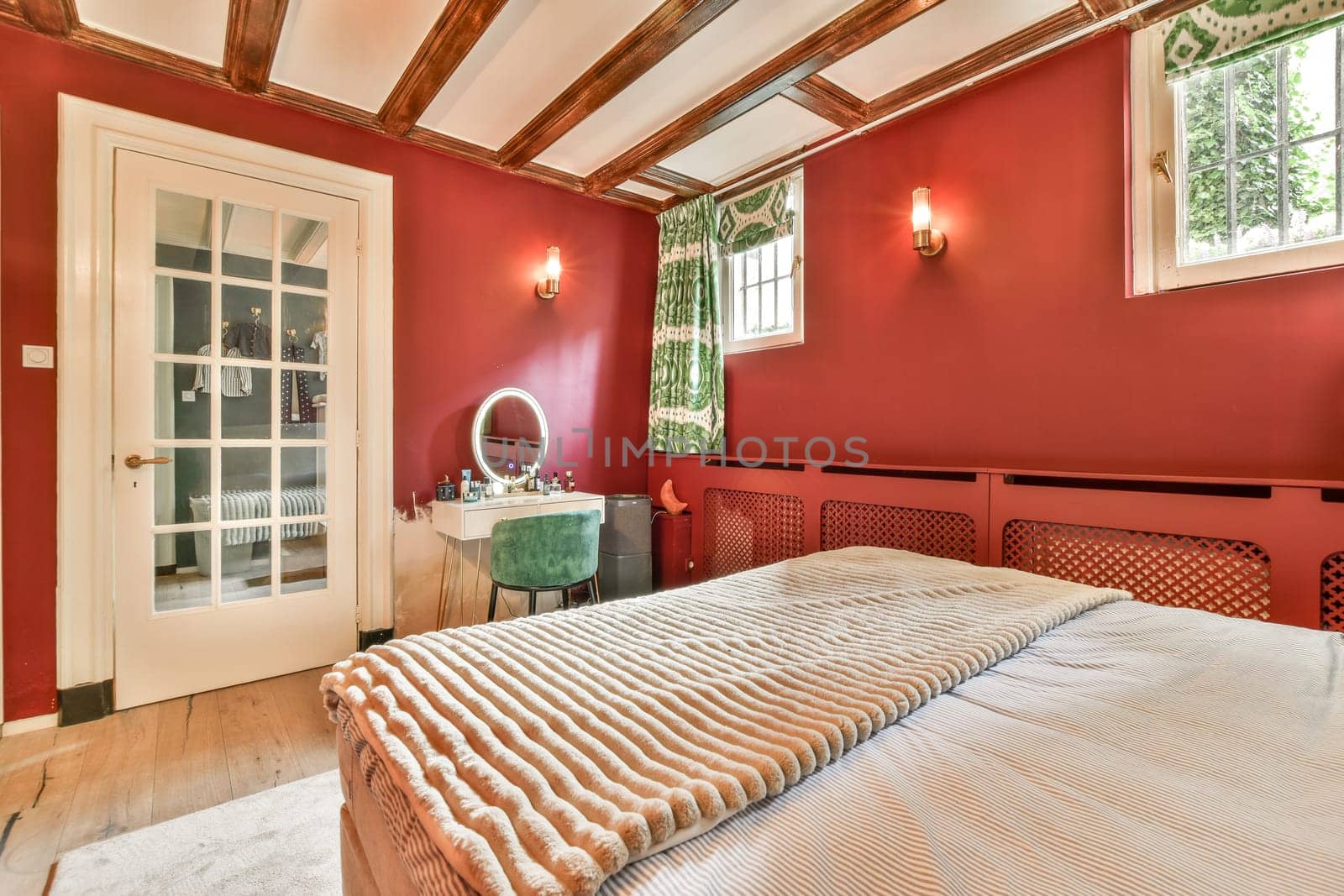 a bed in a room with red walls and wood beams on the ceiling, there is a mirror hanging above it