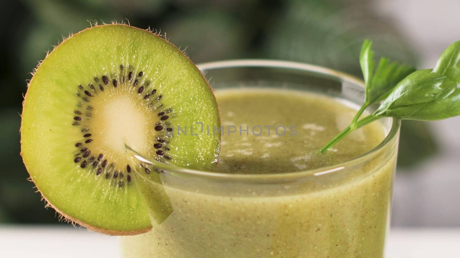 Glasses of green vegetable smoothie. Green vegetable smoothie and ingredients: Kiwi, lemon and herbs.