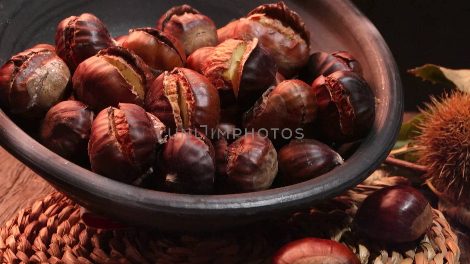 Roasted chestnuts on a rustic wooden table with autumn leaves in the background.