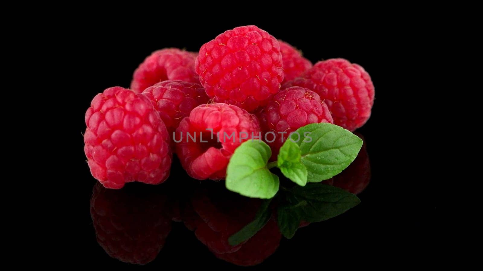 Raspberries with leaves isolated on black background