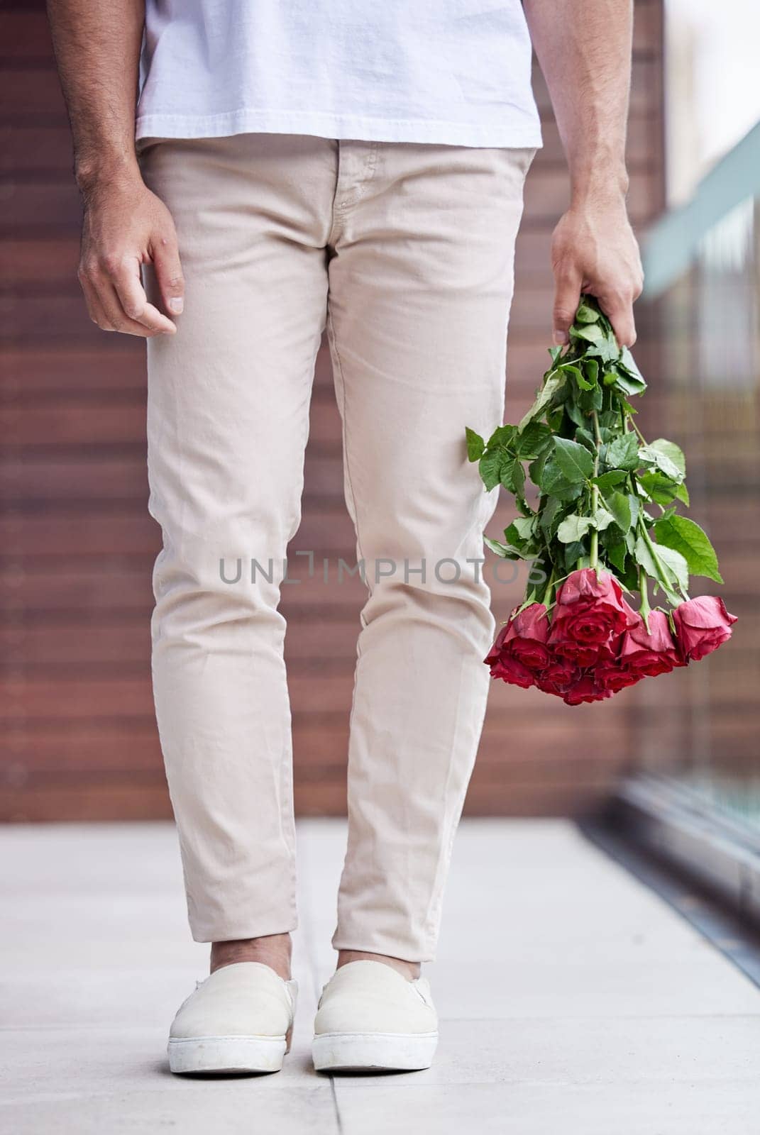 Hands, legs and man with bouquet of roses for date, romance and hope for valentines day. Love confession, romantic floral gift and person holding flowers, standing outside for proposal or engagement by YuriArcurs