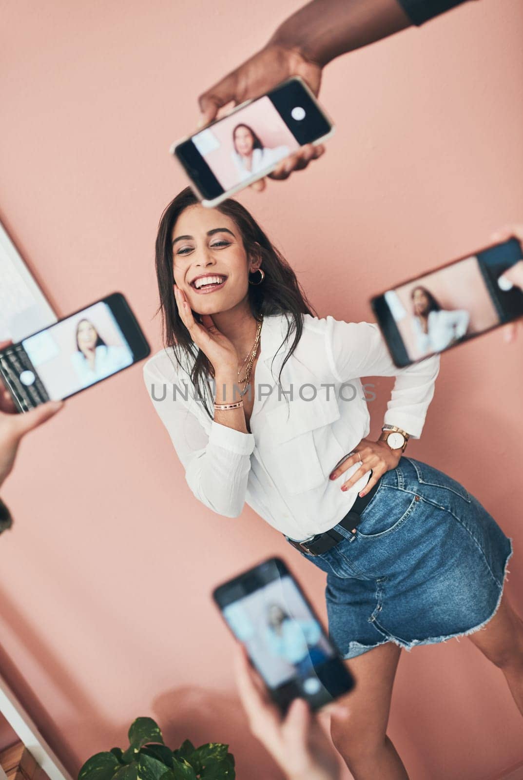 Everyone wants to know her secret. a beautiful young woman having her picture taken on multiple phones