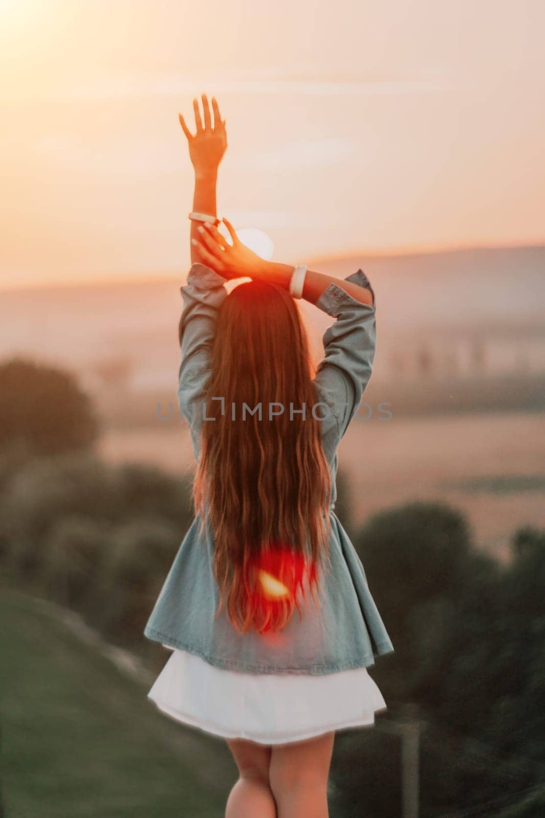 Romantic beautiful bride in white dress posing with sea and mountains in background. Stylish bride standing back on beautiful landscape of sea and mountains on sunset