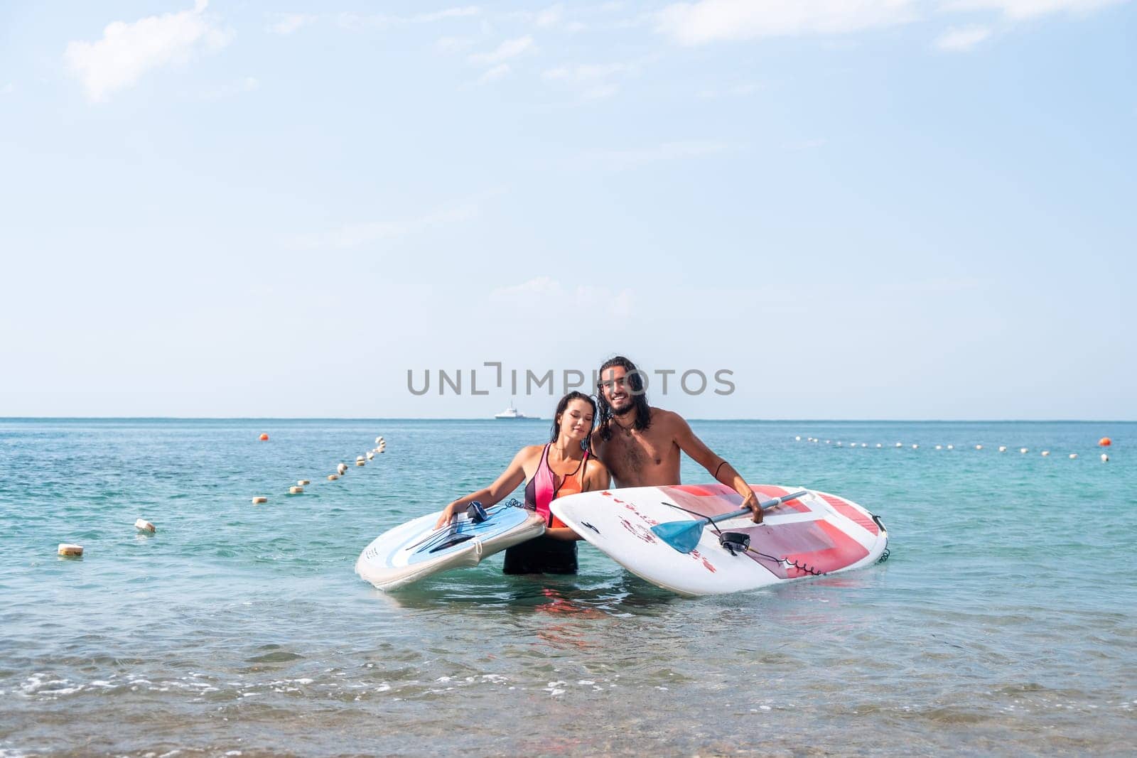 Close up shot of beautiful young caucasian woman with black hair and freckles looking at camera and smiling. Cute woman portrait in a pink bikini posing on a volcanic rock high above the sea