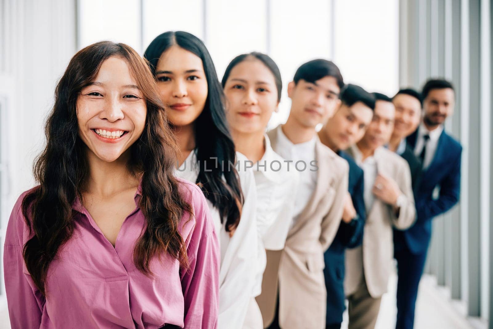 Confident and successful young businesspeople gather indoors, their crossed arms symbolizing unity and achievement. This is a diverse team of professionals who excel in teamwork.