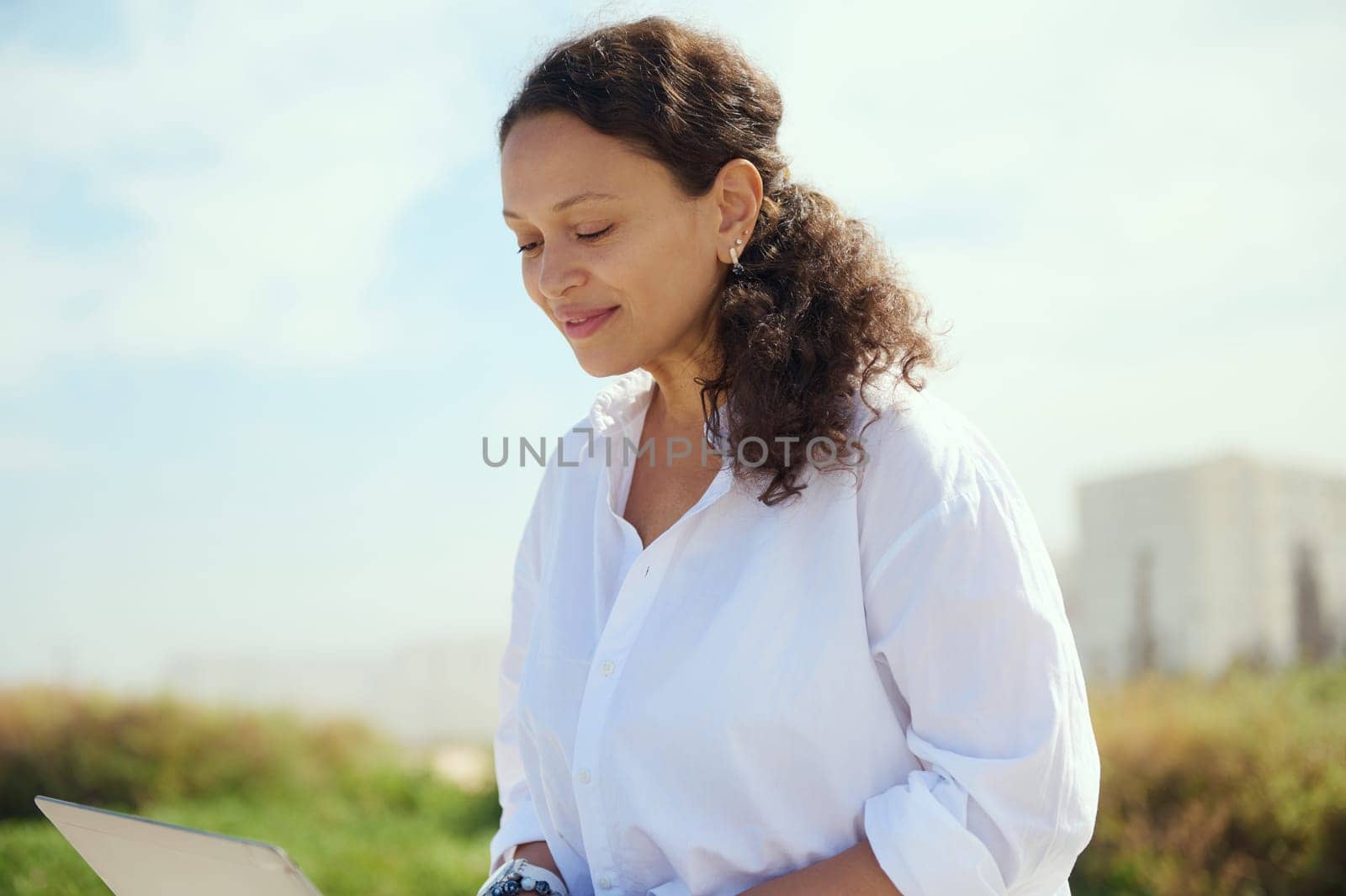 Closeup portrait of a confident charming ethnic curly haired female freelancer entrepreneur, programmer developer telecommuting outdoors. People. Online job. Remote work and internet business concept