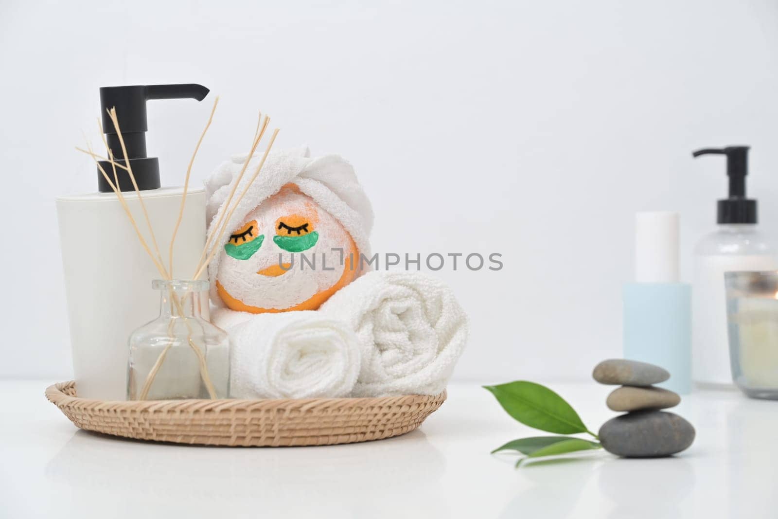 Orange with patches under eyes and towels on white table. Spa treatment and self care concept by prathanchorruangsak