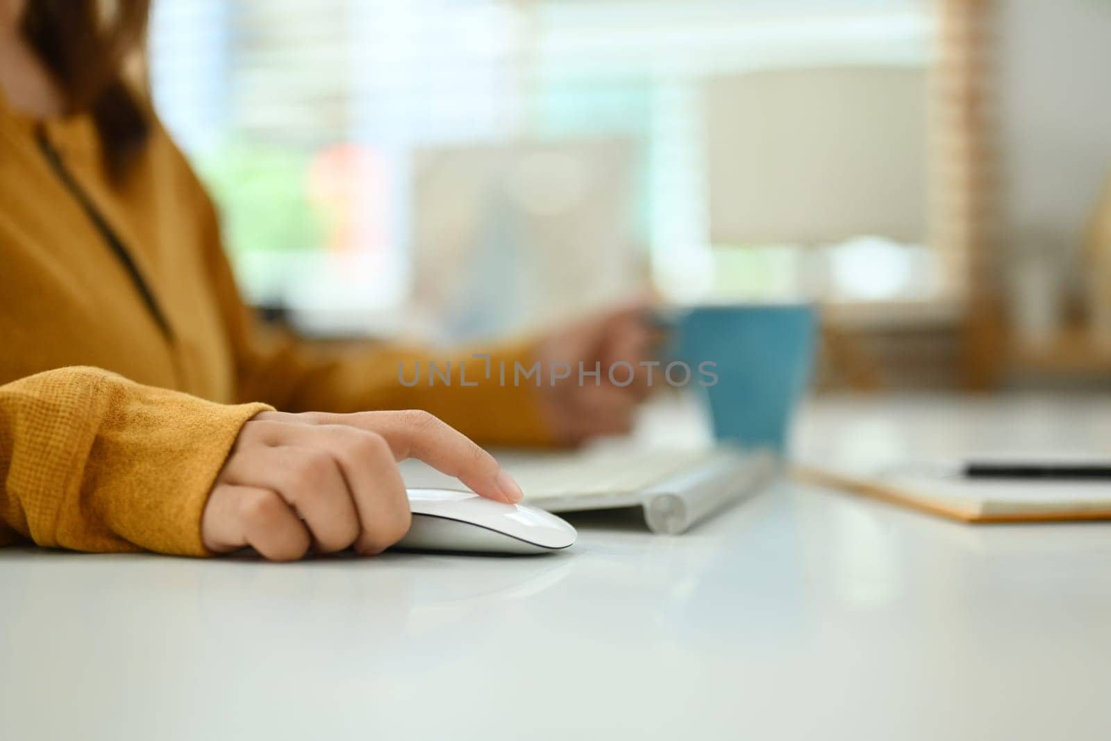 Closeup woman hands using wireless mouse while working on computer at table at home.