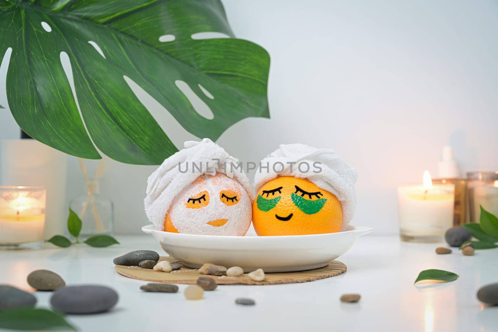 Two orange fruits in face mask looking like in bath or Onsen. Spa treatment and self care concept.