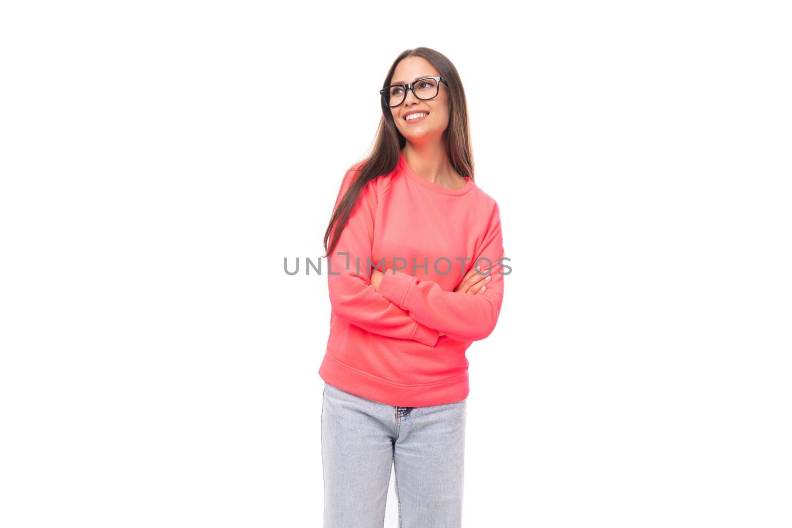 pretty young brunette caucasian woman with straight hair is dressed in a pink sweatshirt and jeans among a white background.