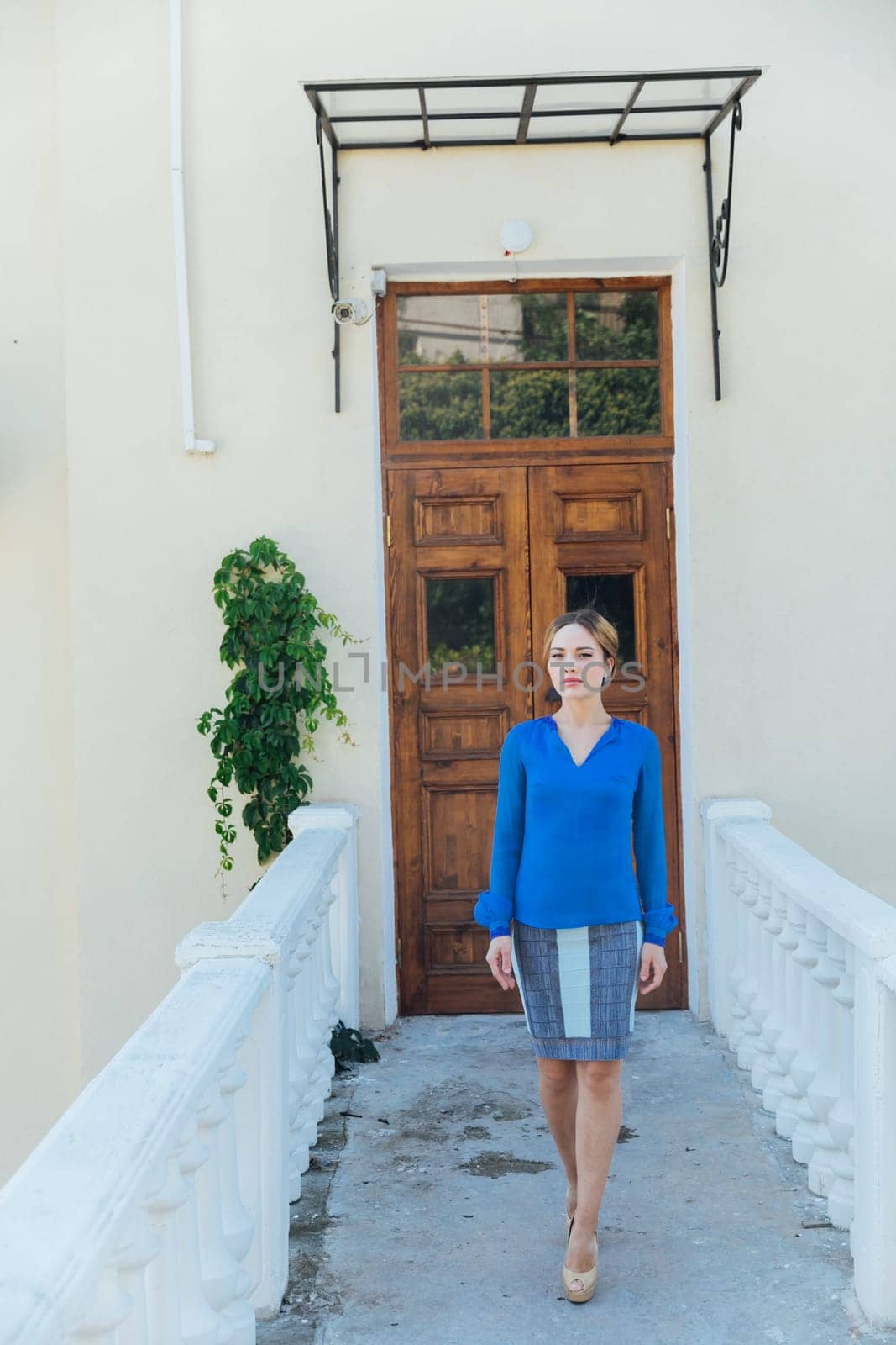 beautiful woman in blue clothes stands on the street at the door of the front door.