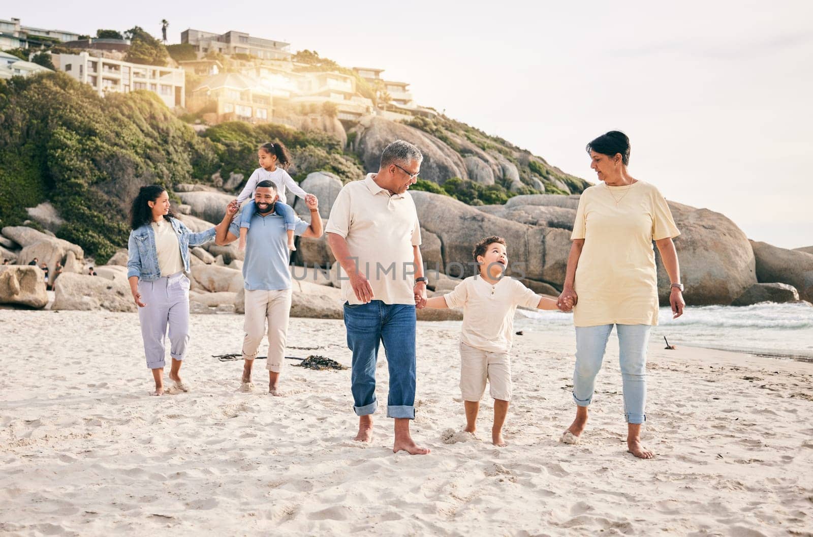 Big family, holding hands and walking at a beach for travel, vacation and fun in nature together. Freedom, parents and children relax with grandparents at the sea on holiday, trip or ocean adventure.